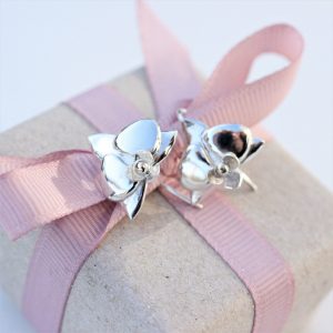 Øreringe der ligner orkide blomster i sølv som ligger oven på en indpakket gave.